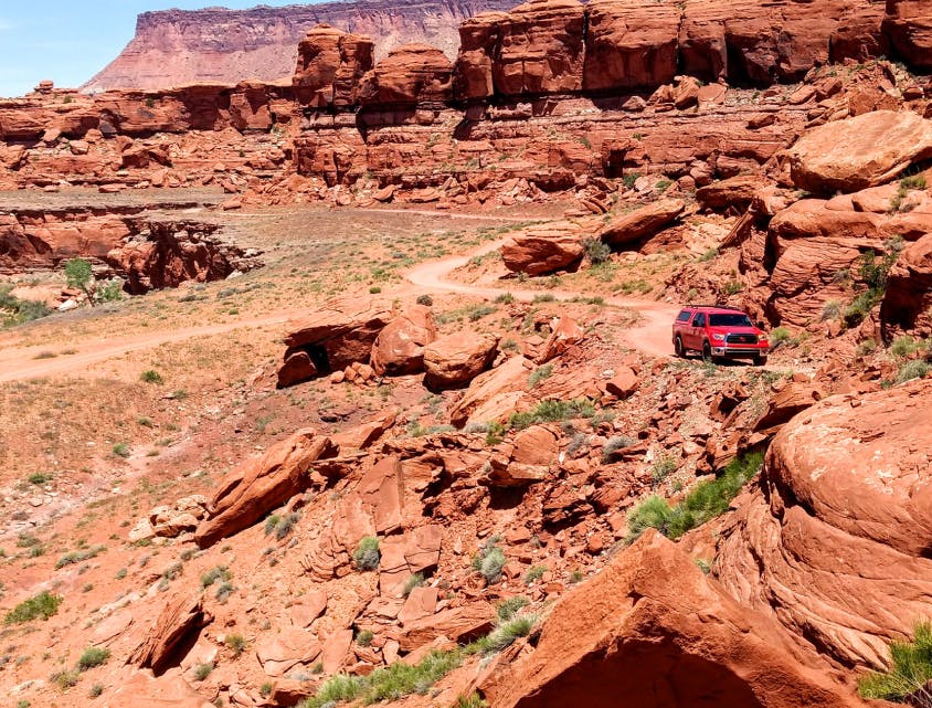 Red car driving through desert rocks